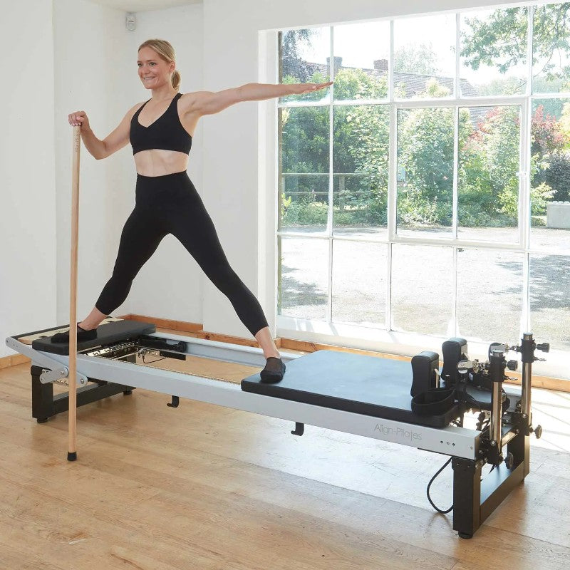 Align-Pilates Platform Extender For A-Series Reformer model standing with gondola pole on platform window background