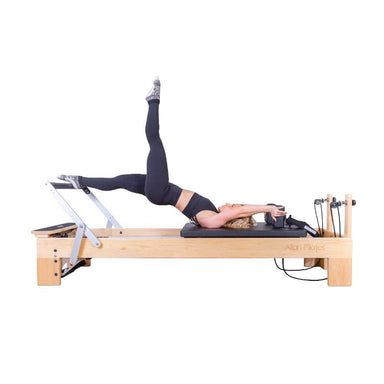 Align-Pilates M8-Pro RC Maple Wood Studio Reformer with model using foot bar side view white background