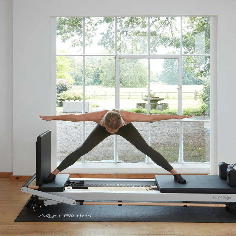 Align-Pilates Platform Extender For C-Series Reformer with model using reformer side view window in the background 